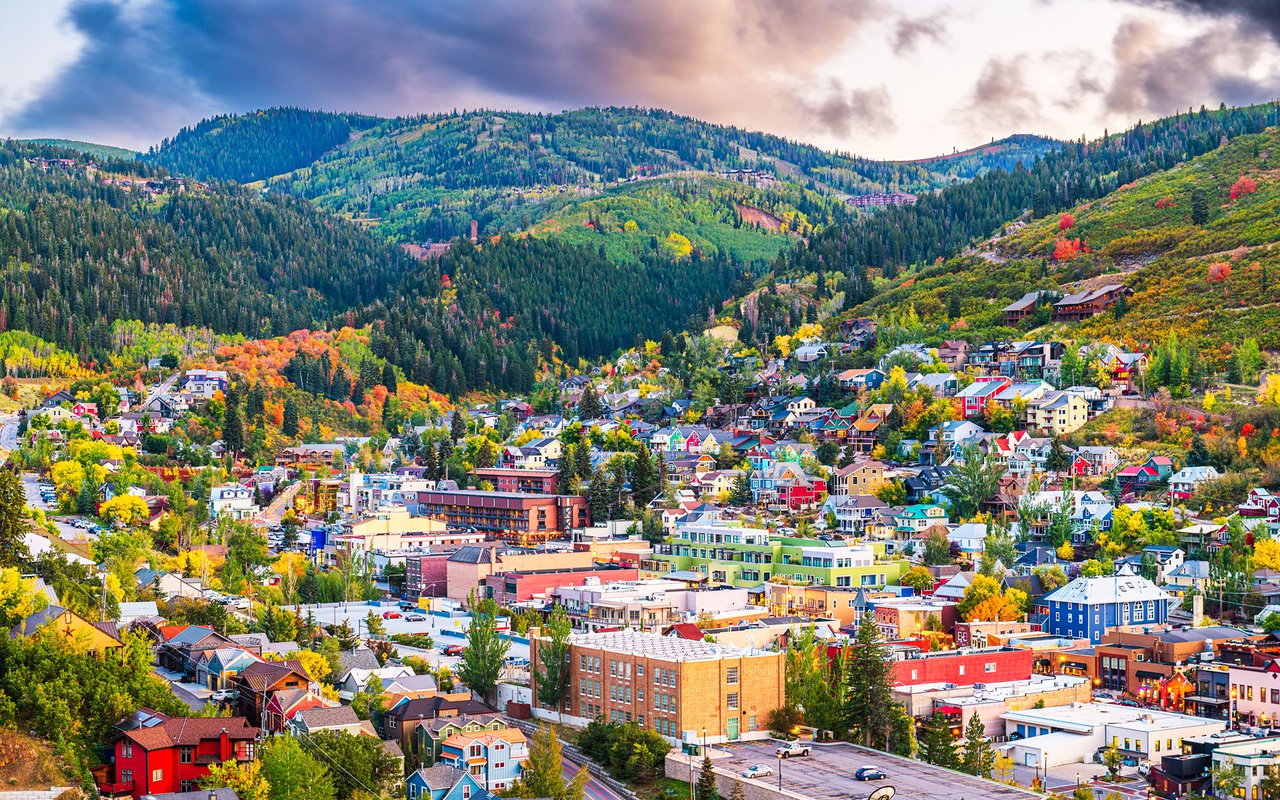 Mountain town in an autumn valley, with colorful hillside foliage and buildings filling the foreground.