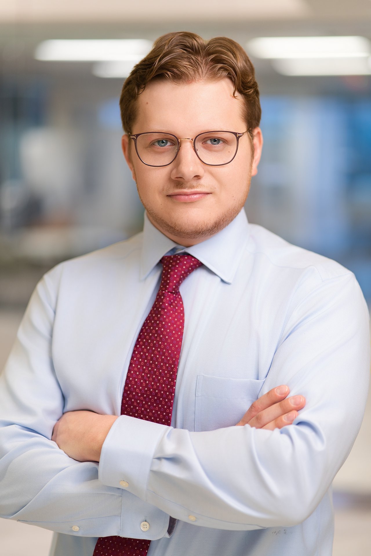 Michael Lewis in glasses and a burgundy tie, standing with his arms crossed.