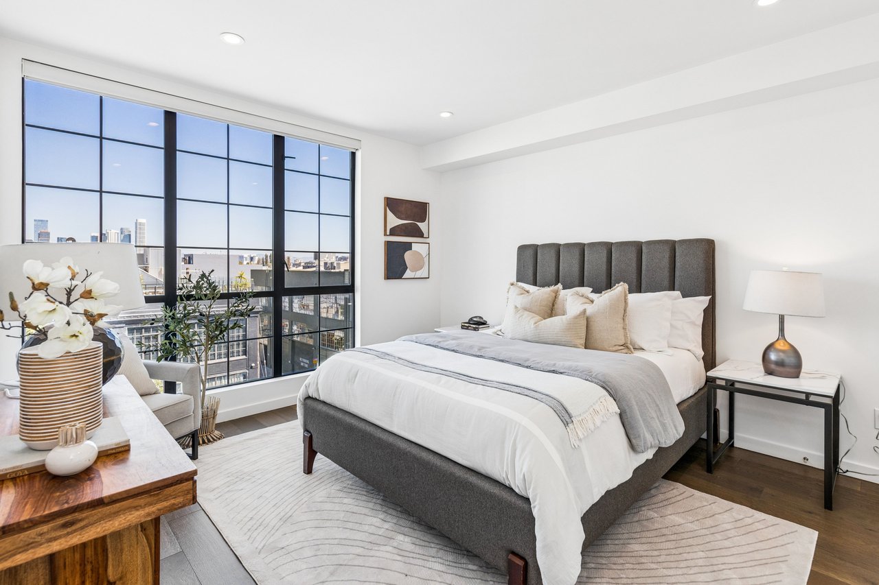 Serene bedroom retreat with large windows framing city views, abundant natural light, and a calming ambiance—your private oasis in the city.