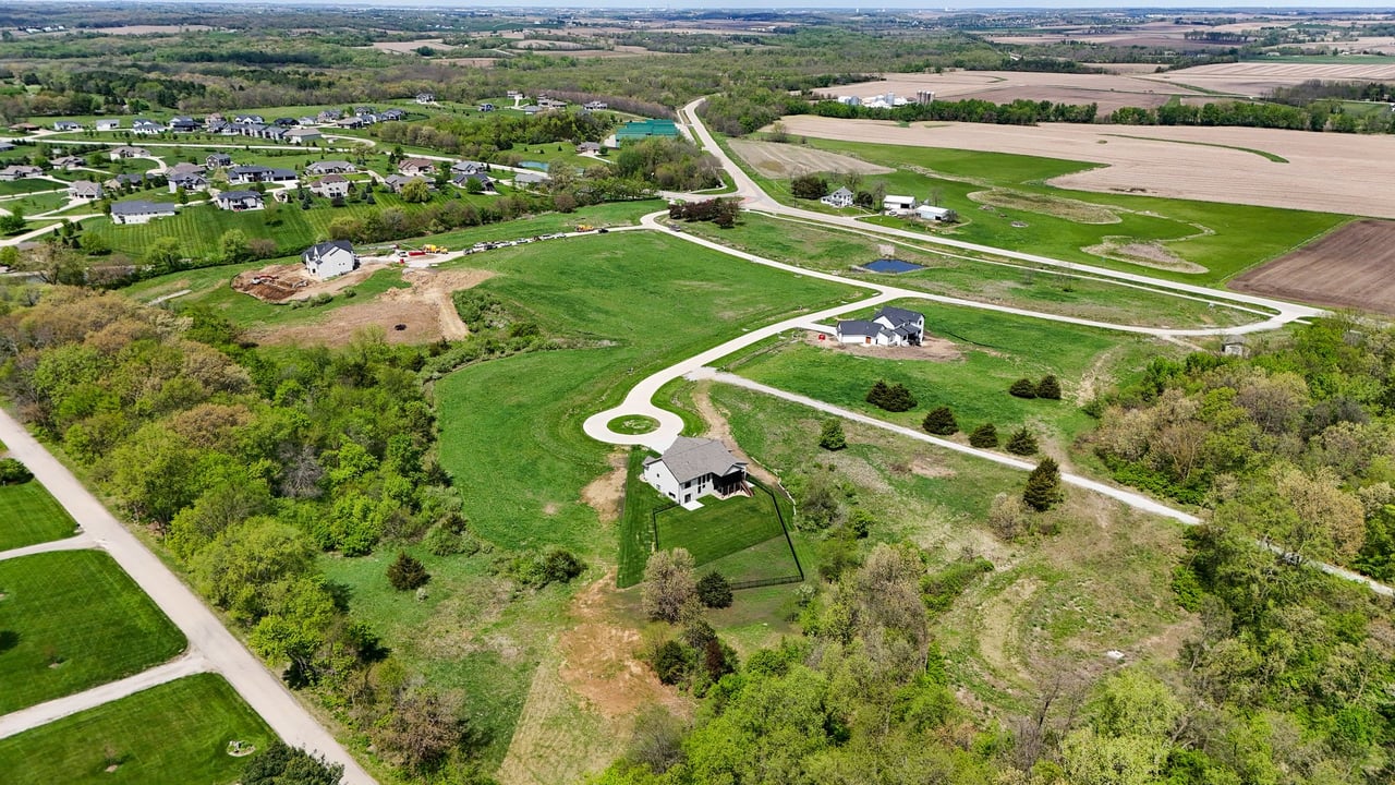 Aerial view of Oak Meadow with winding roads, green lots, scattered homes, and surrounding farmland.