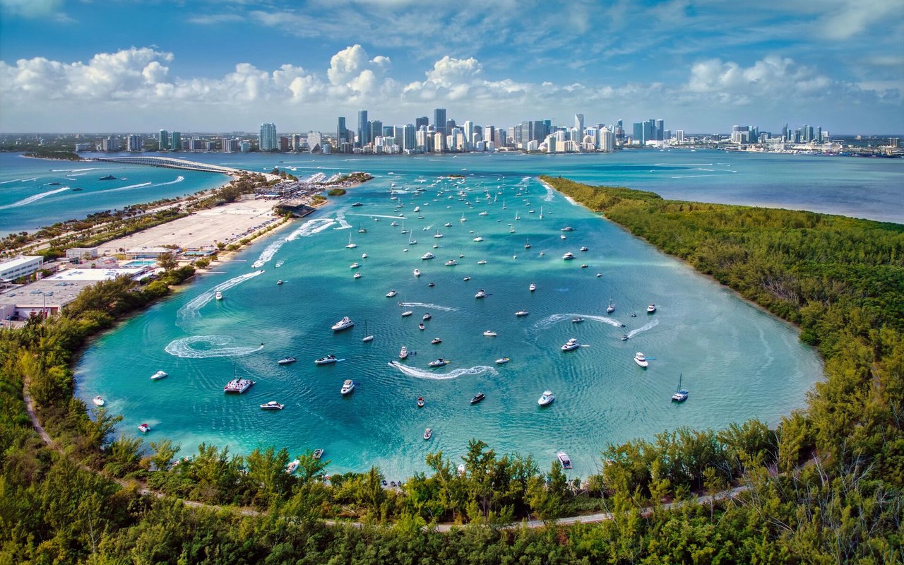 Aerial view of a boat-filled bay with Miami's skyline in the distance.