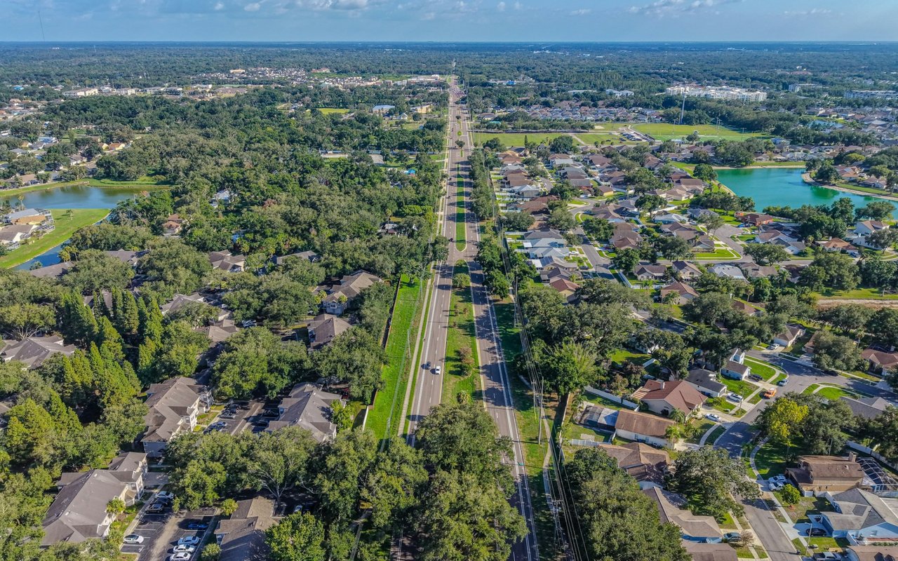 Aerial view of a leafy neighborhood with lakes on either side of a divided road.