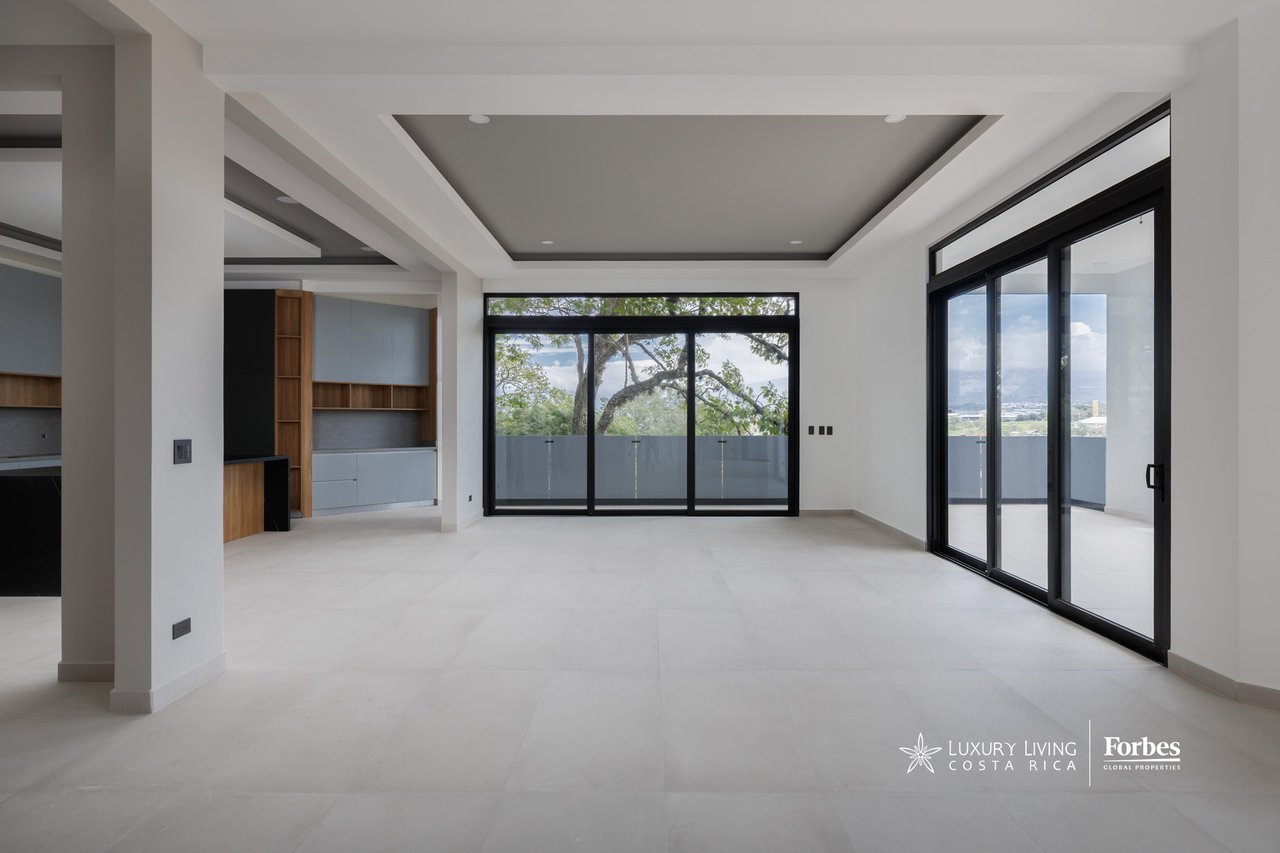 Modern vacant living area with built-in cabinetry and black-framed glass doors opening to a terrace.