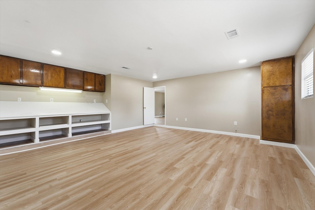 Empty room with wood-look flooring and built-in cabinets and shelving.