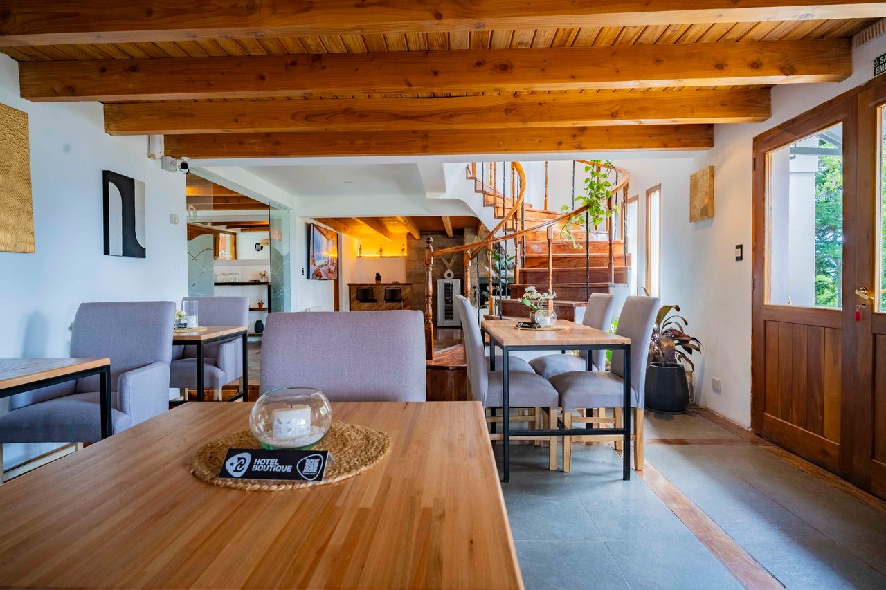 Hotel dining area with timber ceiling beams, wooden tables, and a staircase.