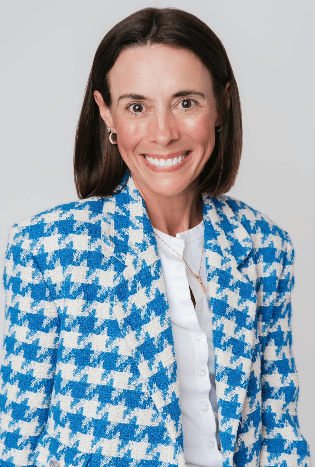 Lindy Brooks smiling in a blue-and-white patterned jacket.