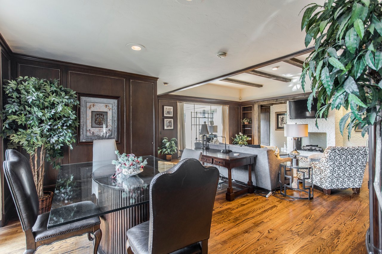 Living and dining room with dark wood paneling, hardwood floors, and a fireplace.