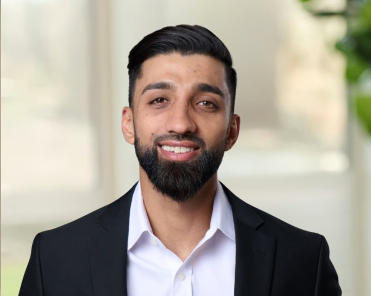 Smiling male real estate agent in a black jacket and white shirt.