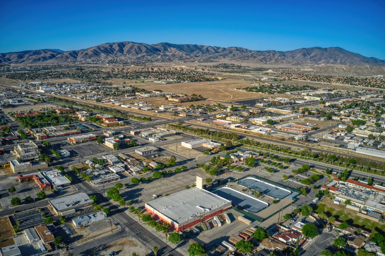 Aerial view of Palmdale with commercial buildings and roads stretching toward dry mountain ranges.