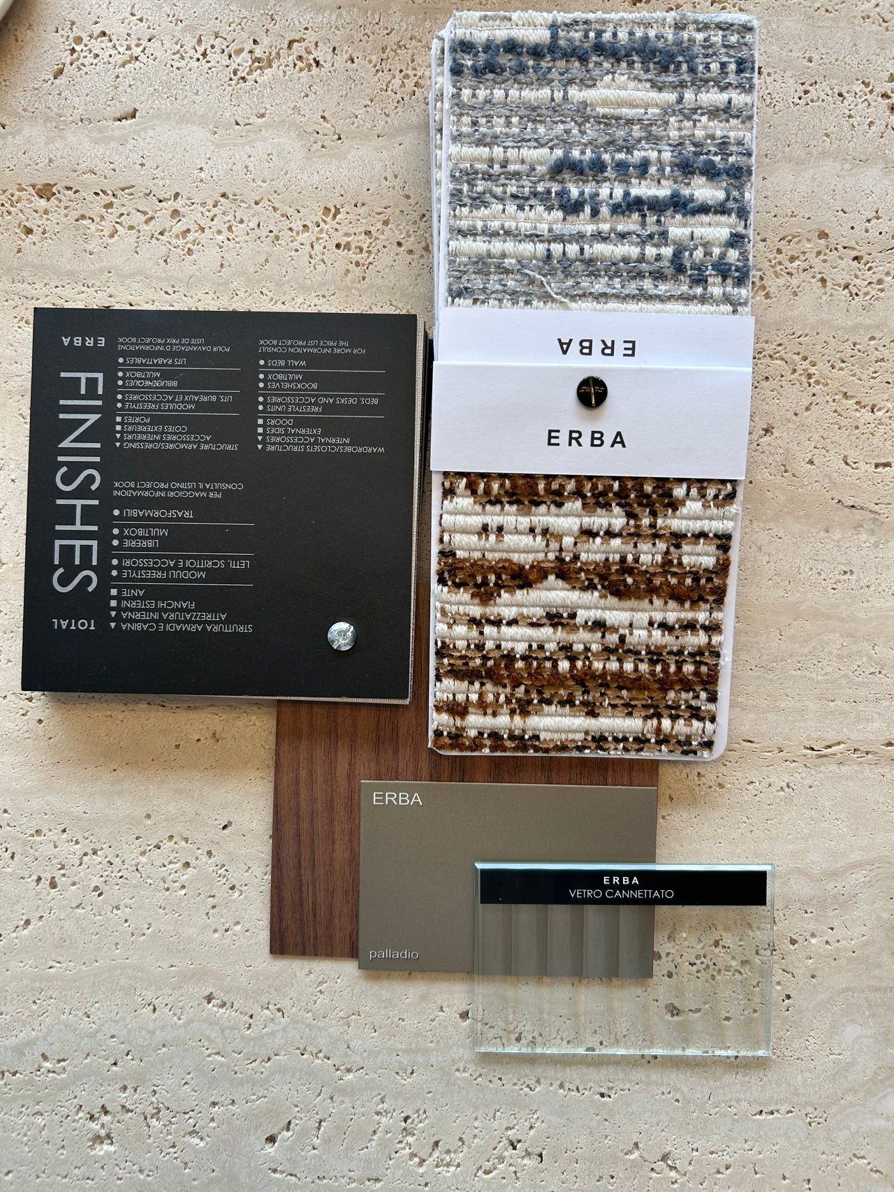 ERBA woven carpet samples, finishes chart, wood sample, and glass panel on a pale stone surface.