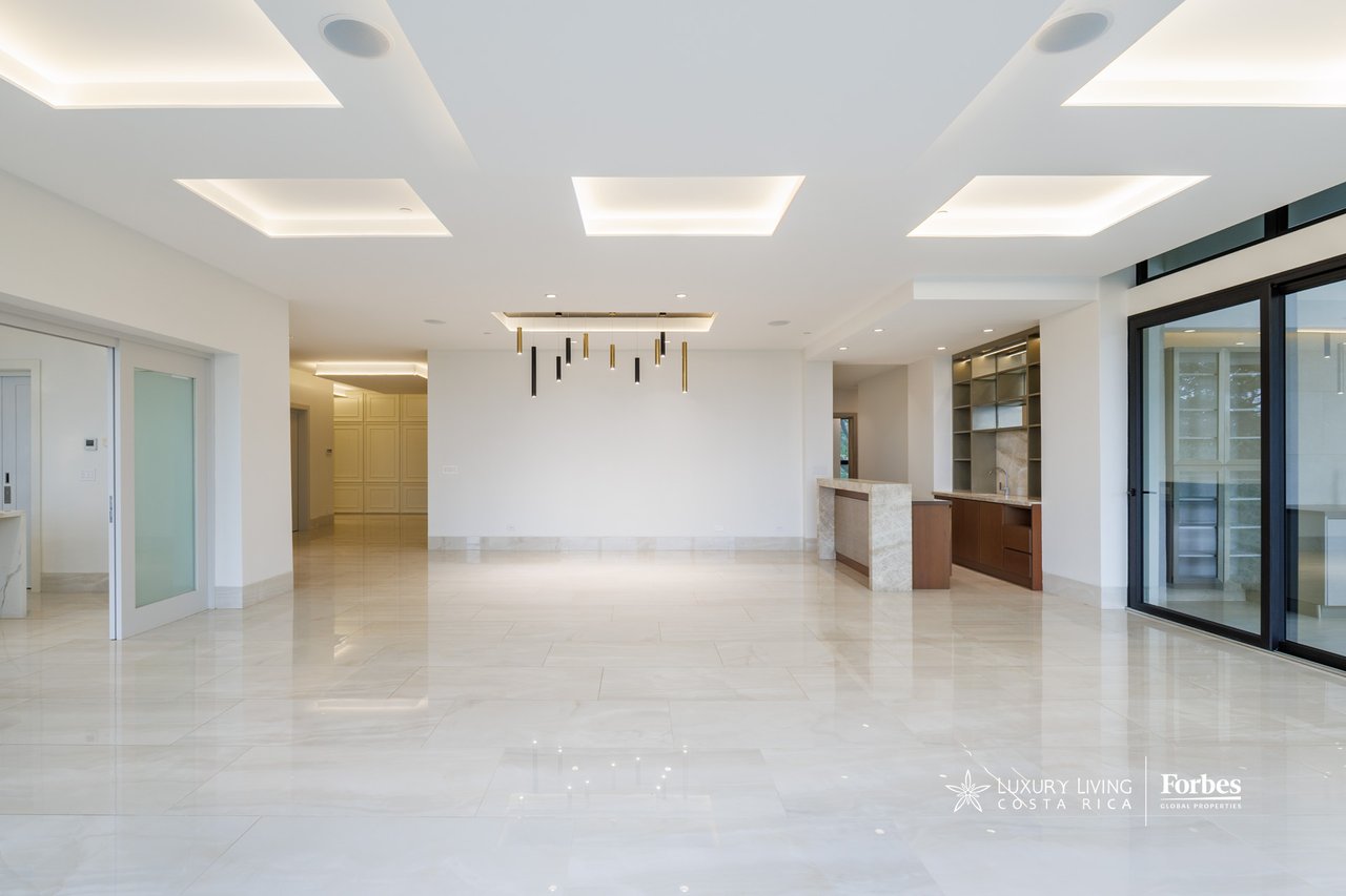 Vacant open-plan apartment with a built-in kitchen, glossy tile floors, and large sliding glass doors.