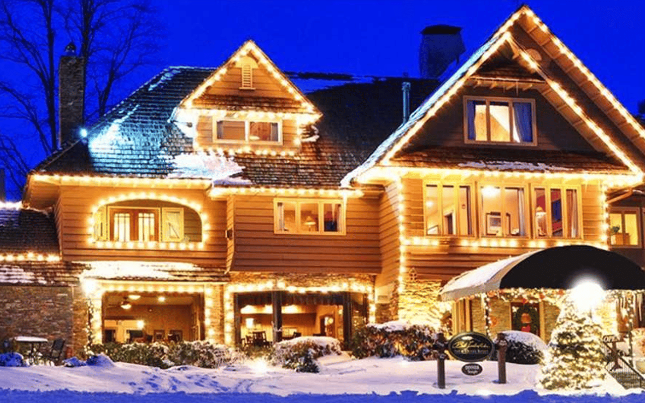 Snow-covered lodge glowing with holiday lights against a deep blue night sky.