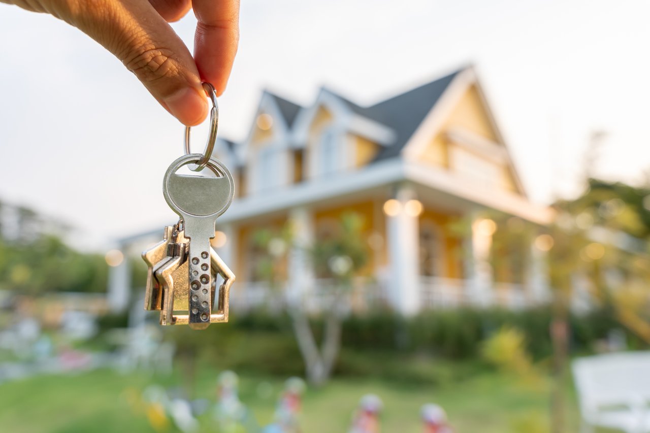 House keys held in front of a softly blurred home.