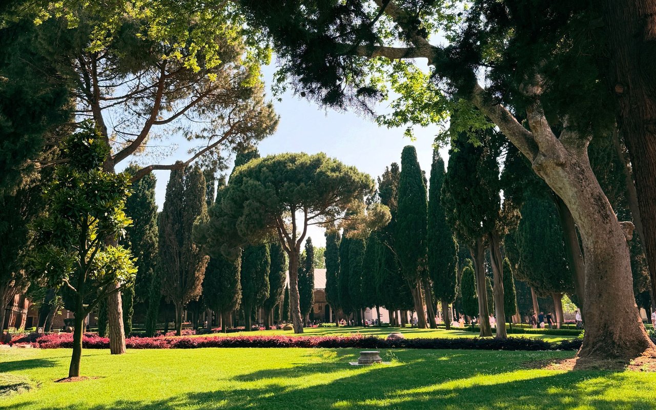 Tree-lined park with bright lawns and flowering garden beds.