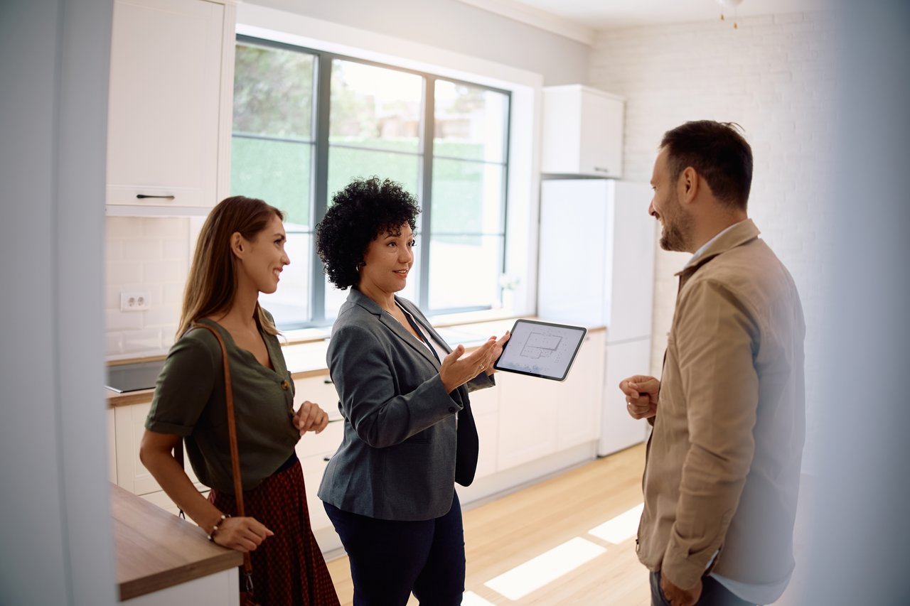 Real estate agent showing home layout to clients using a digital tablet.