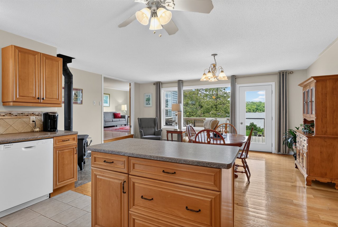 Kitchen with a large wood island and dining area overlooking a lake.