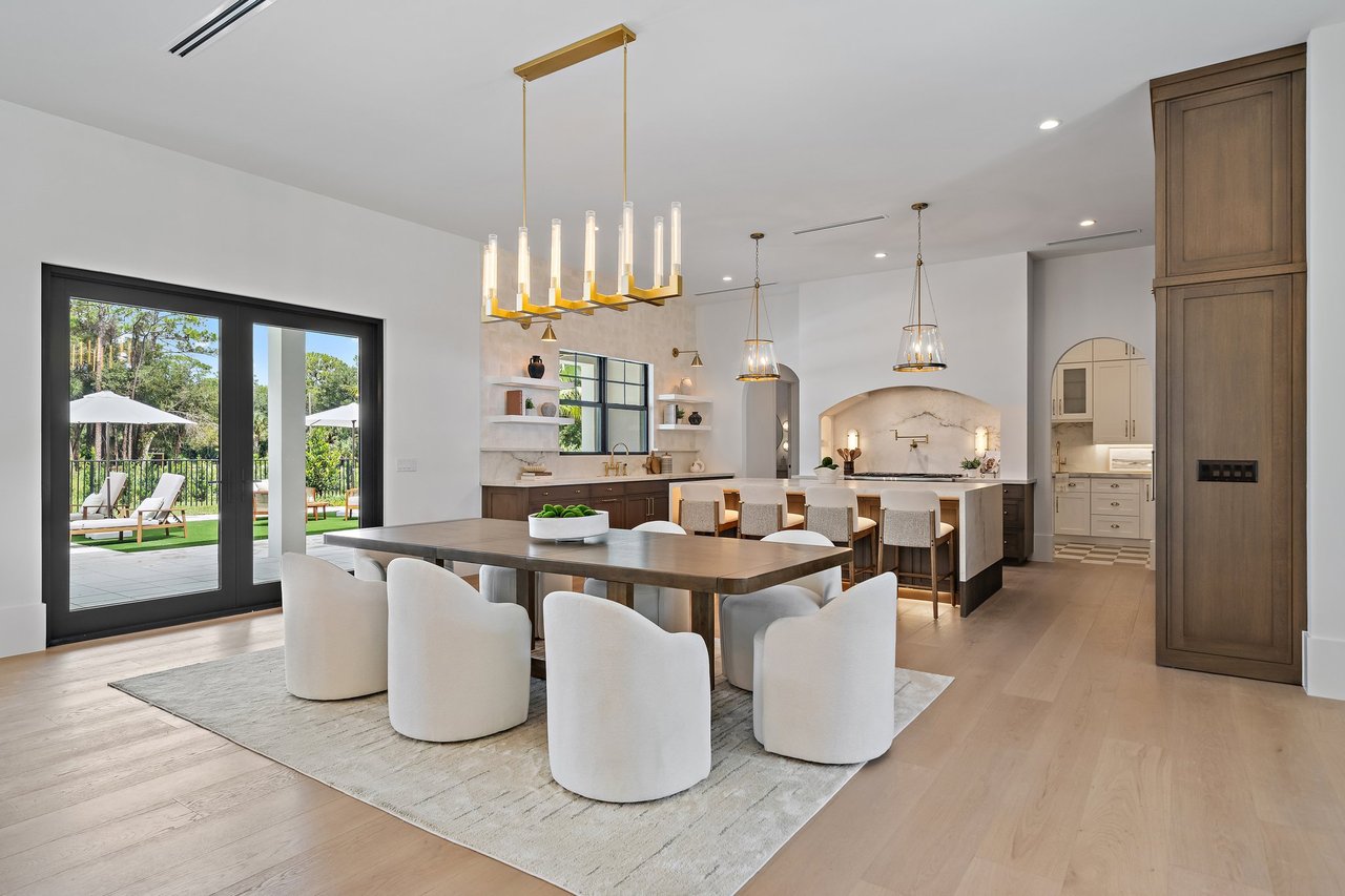 Open kitchen and dining room with a marble island and glass doors opening to a patio.