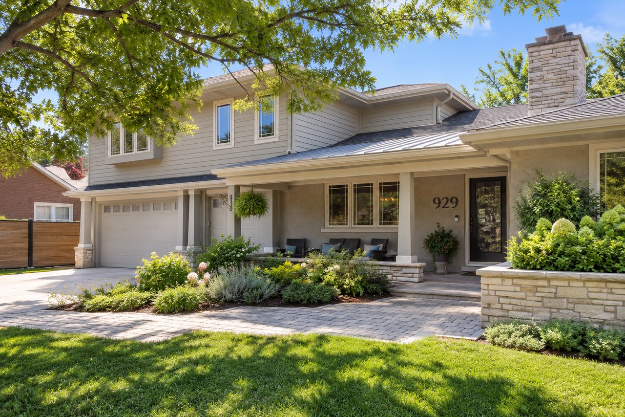 Updated two-story home in Clyde Estates, Downers Grove, Illinois, featuring a covered front porch, landscaped yard, mature trees, and attached garage.