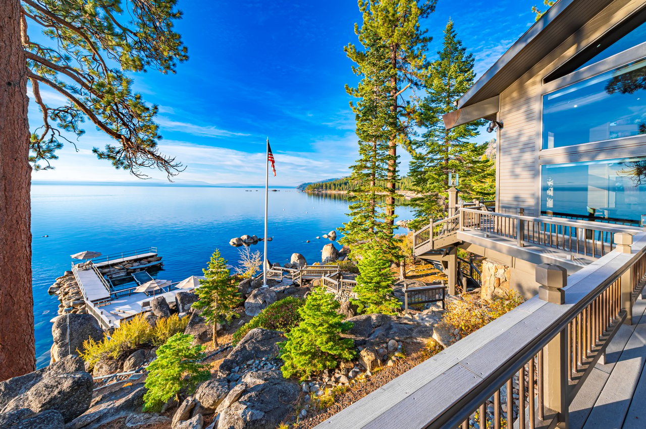 Lakeside home with a broad deck overlooking a rocky shore and private dock.