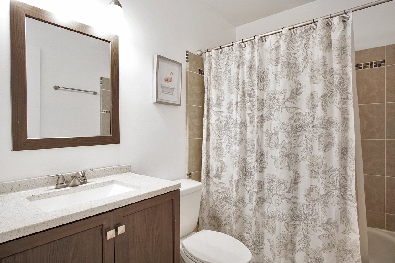 A clean bathroom featuring a shower curtain and a toilet, showcasing a simple and functional design.