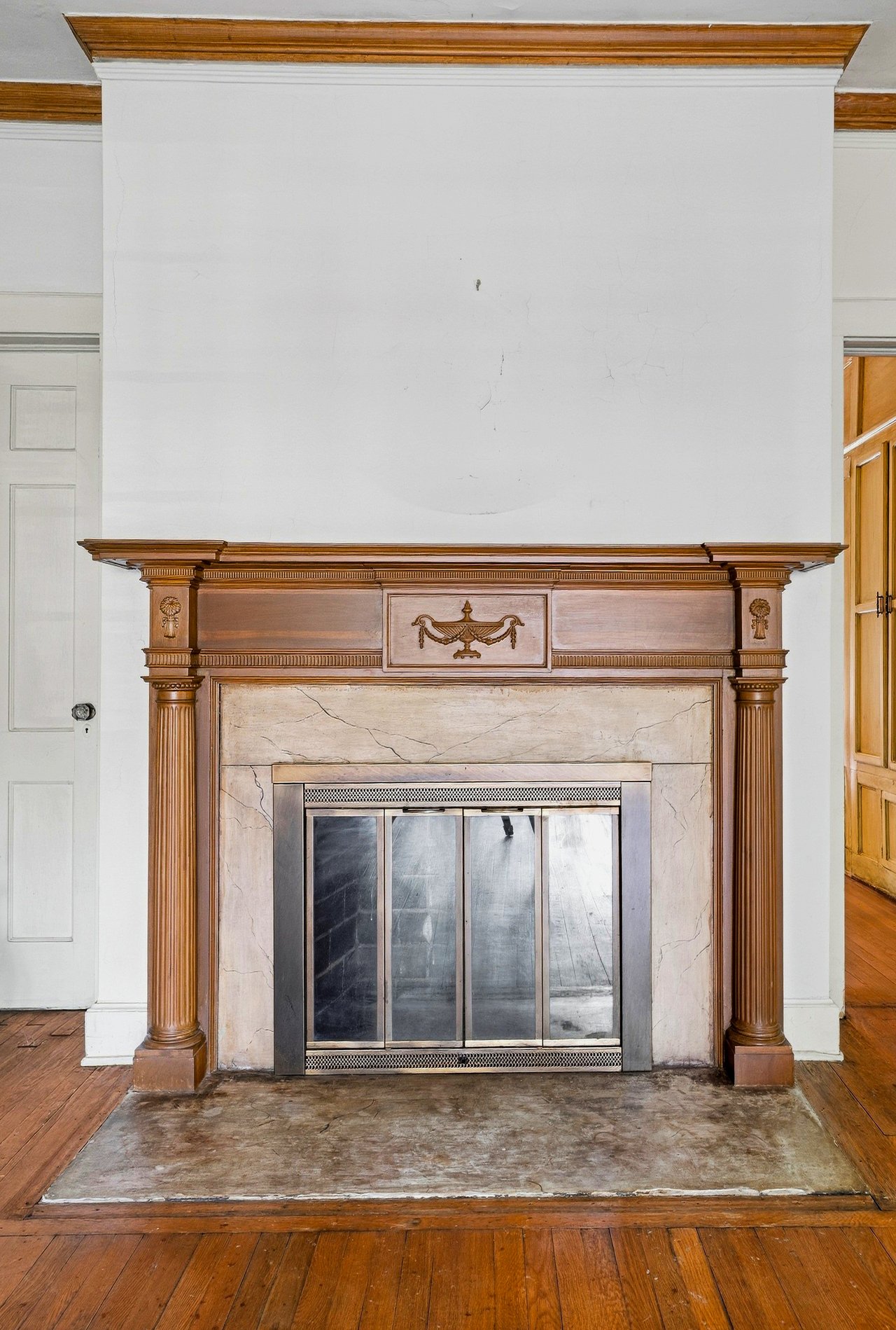 Ornate carved wood fireplace with a marble surround and metal screen.