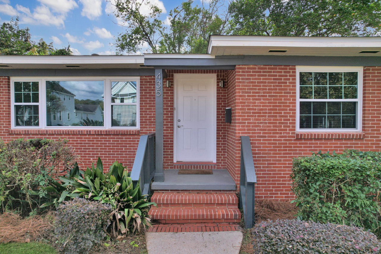 A small brick house featuring a welcoming front porch and steps leading to the entrance.