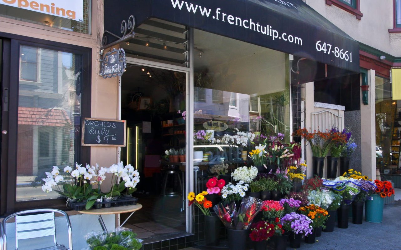 The French Tulip flower shop displays colorful bouquets and potted flowers along the sidewalk.