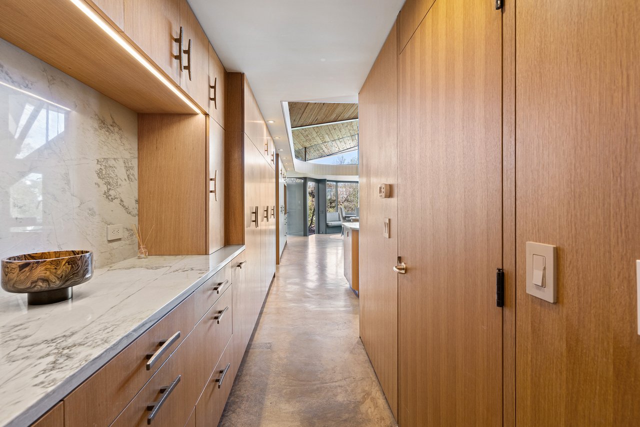 Butler's pantry corridor with rift-sawn white oak cabinetry, Calacatta Macaubas quartzite counters and polished concrete floors, Lick Creek Lodge, Spicewood, Texas.