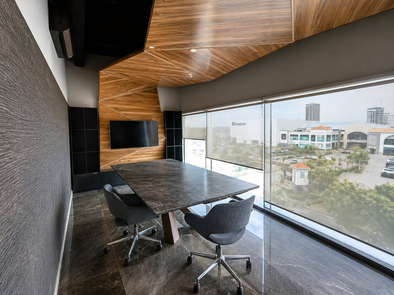 Conference room with a stone table, sculpted wood accents, and windows overlooking commercial buildings.