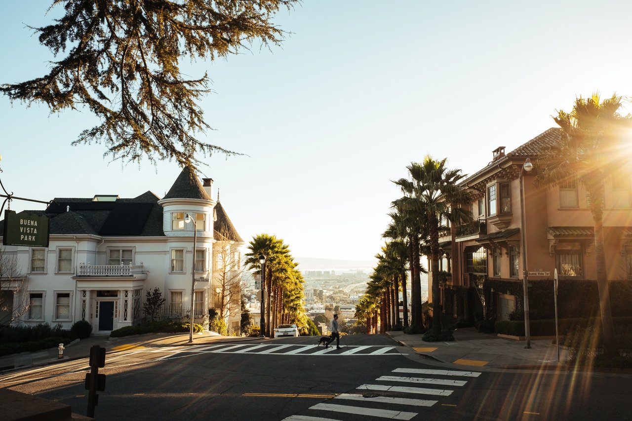 San Francisco residential street descending between homes and palm trees in warm evening light.