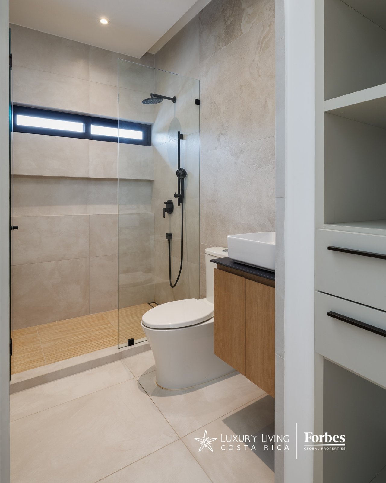 Modern bathroom with a glass shower, black fixtures, and a wood vanity.