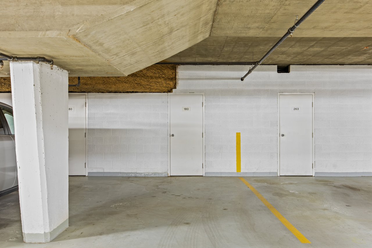 Underground parking garage with a yellow stall line and storage locker door marked 180.