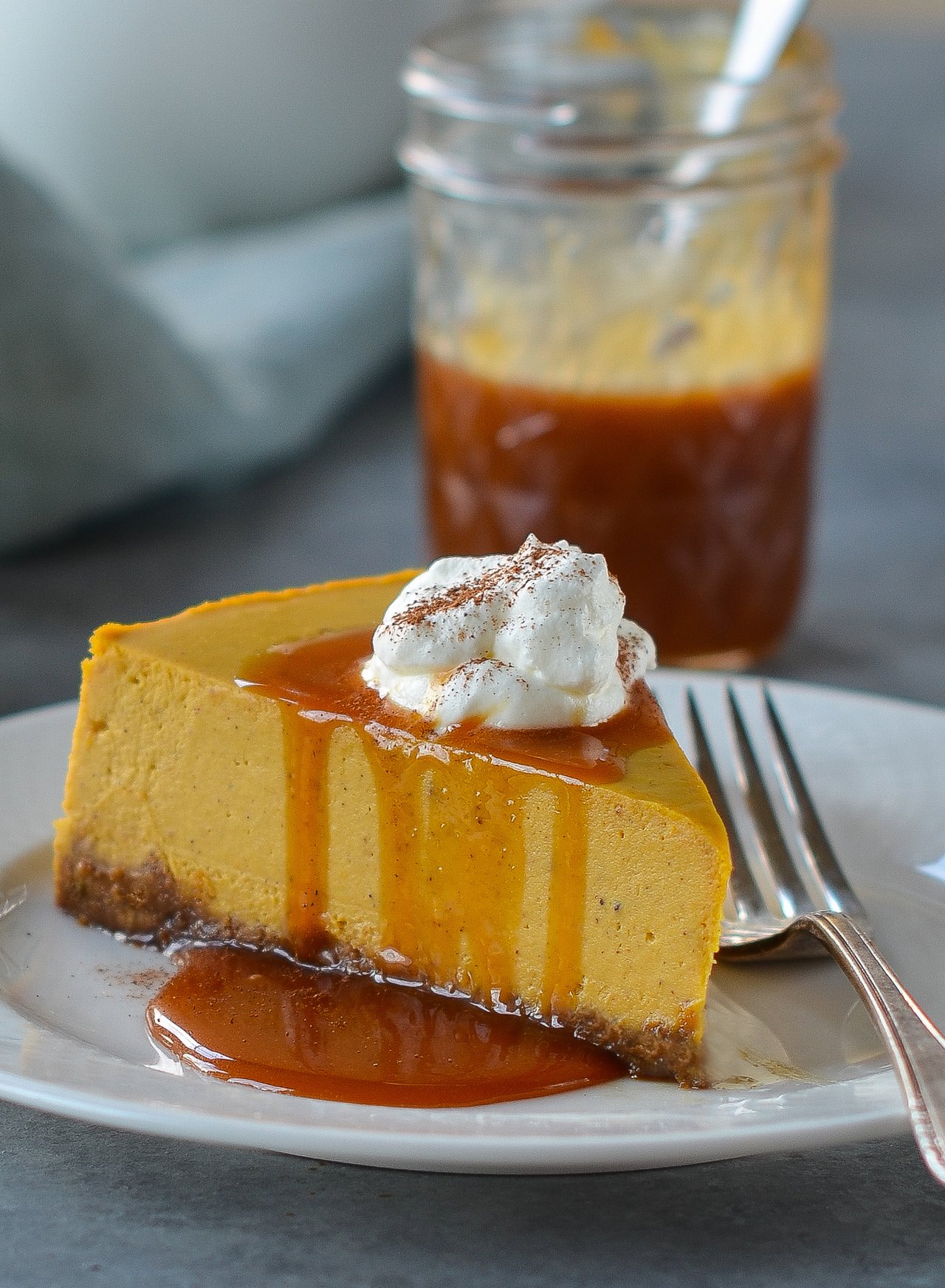 Pumpkin cheesecake with gingersnap crust, drizzled with caramel sauce and topped with whipped cream.