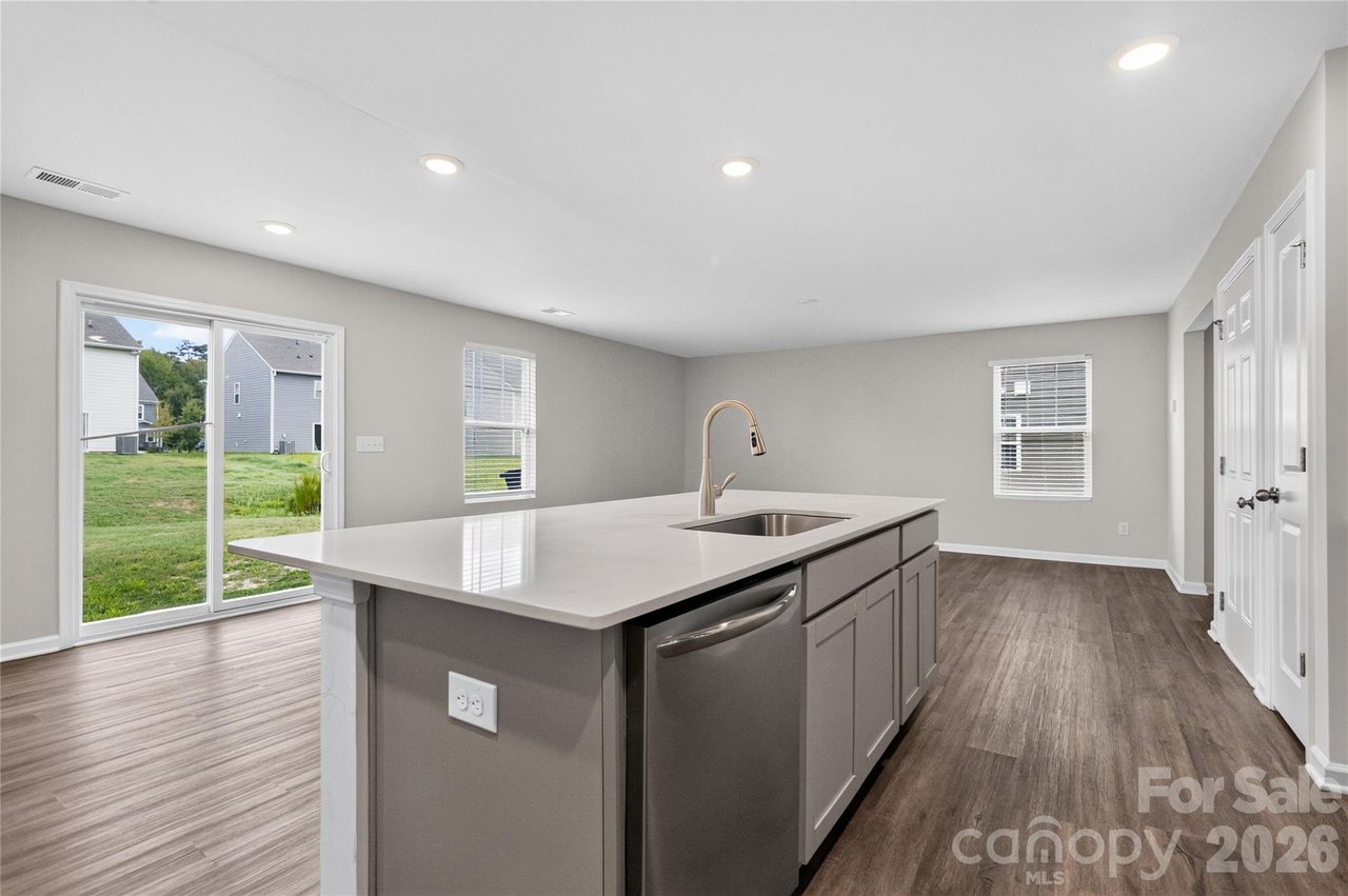 Kitchen with a large gray island, sink and dishwasher beside sliding glass doors to the backyard.