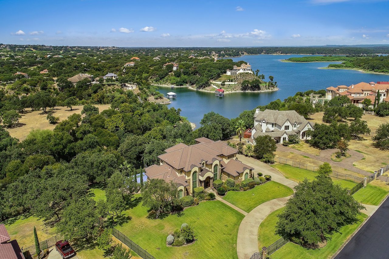Aerial view of the Mediterranean-style estate at 25715 Cliff Circle in the gated Lakecliff on Lake Travis community, Spicewood, Texas, set on nearly 1.5 acres with a Lake Travis cove in the background.
