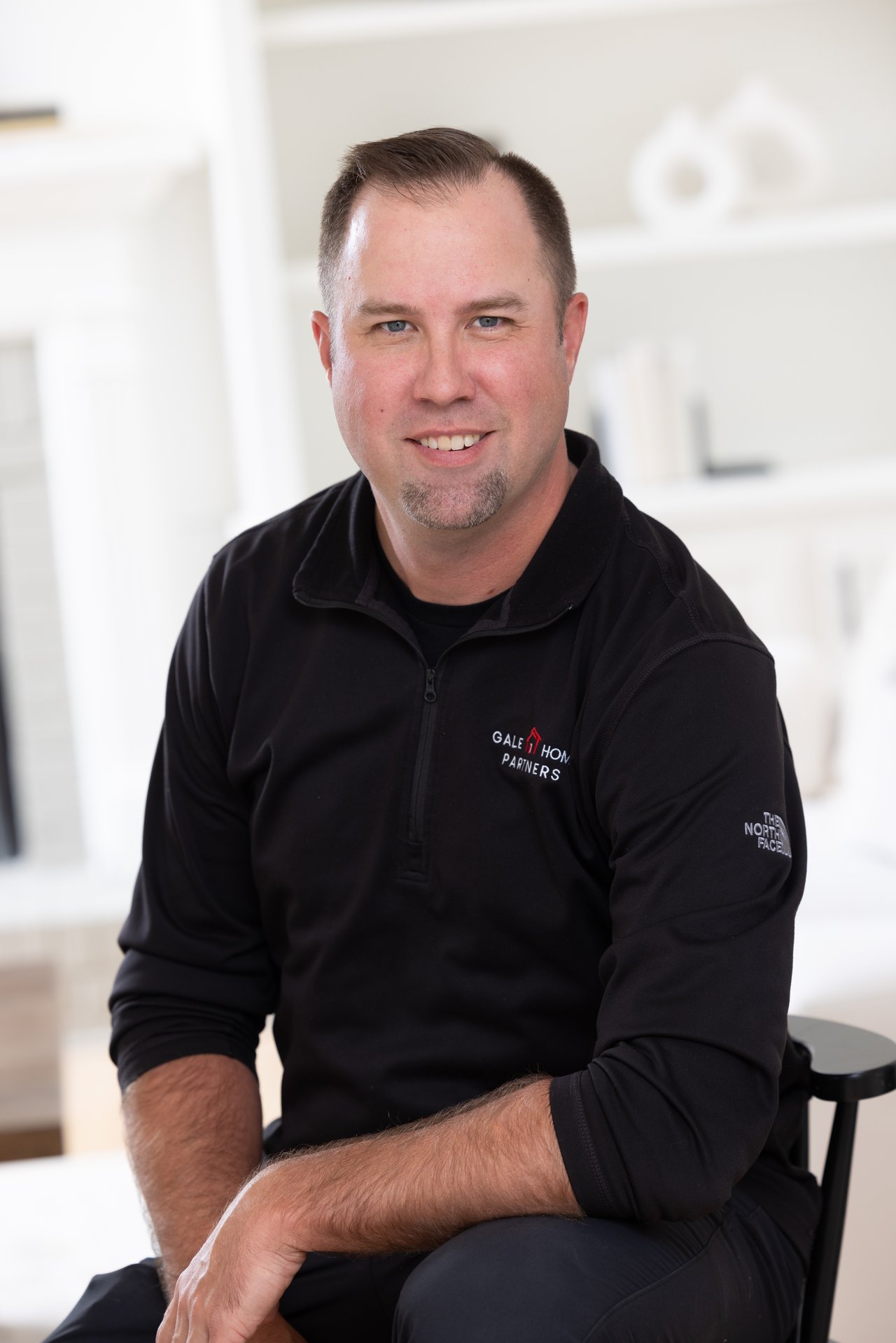John Gale seated in a black zip-up top with Gale Home Partners branding.