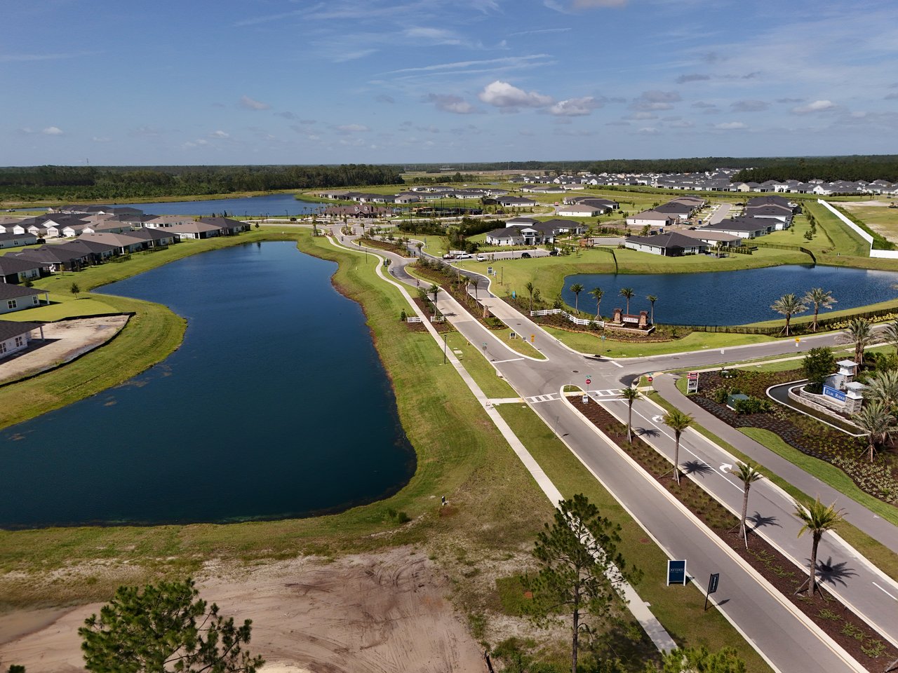 Aerial view of Elm Ridge homes and curving streets beside two ponds.