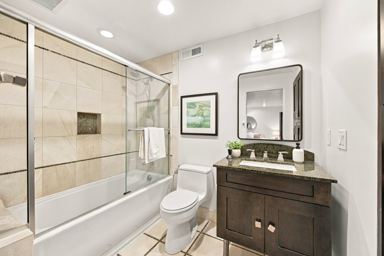 Bathroom with a glass-enclosed tub and shower beside a dark wood vanity.
