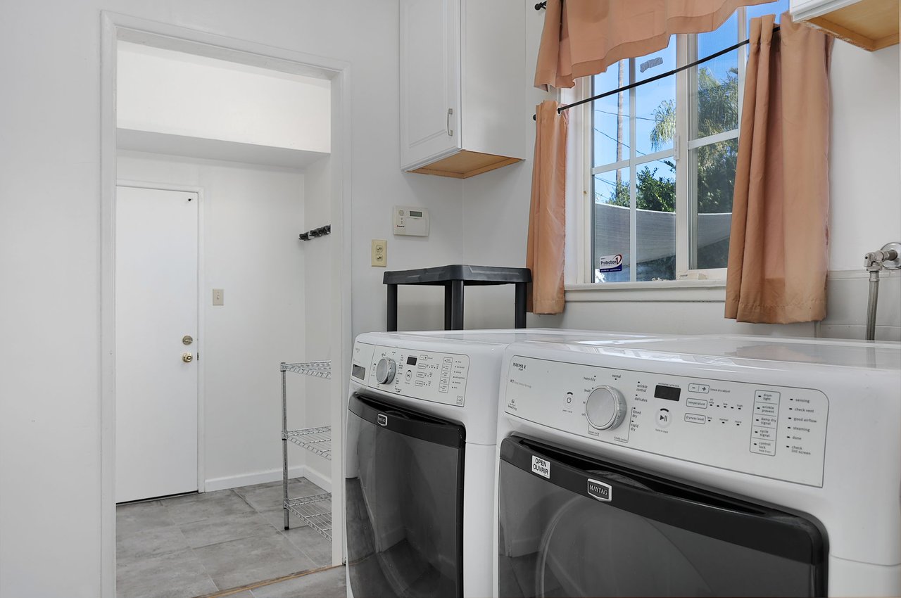 Bright laundry room with Maytag washer and dryer, storage cabinetry, and tile floors