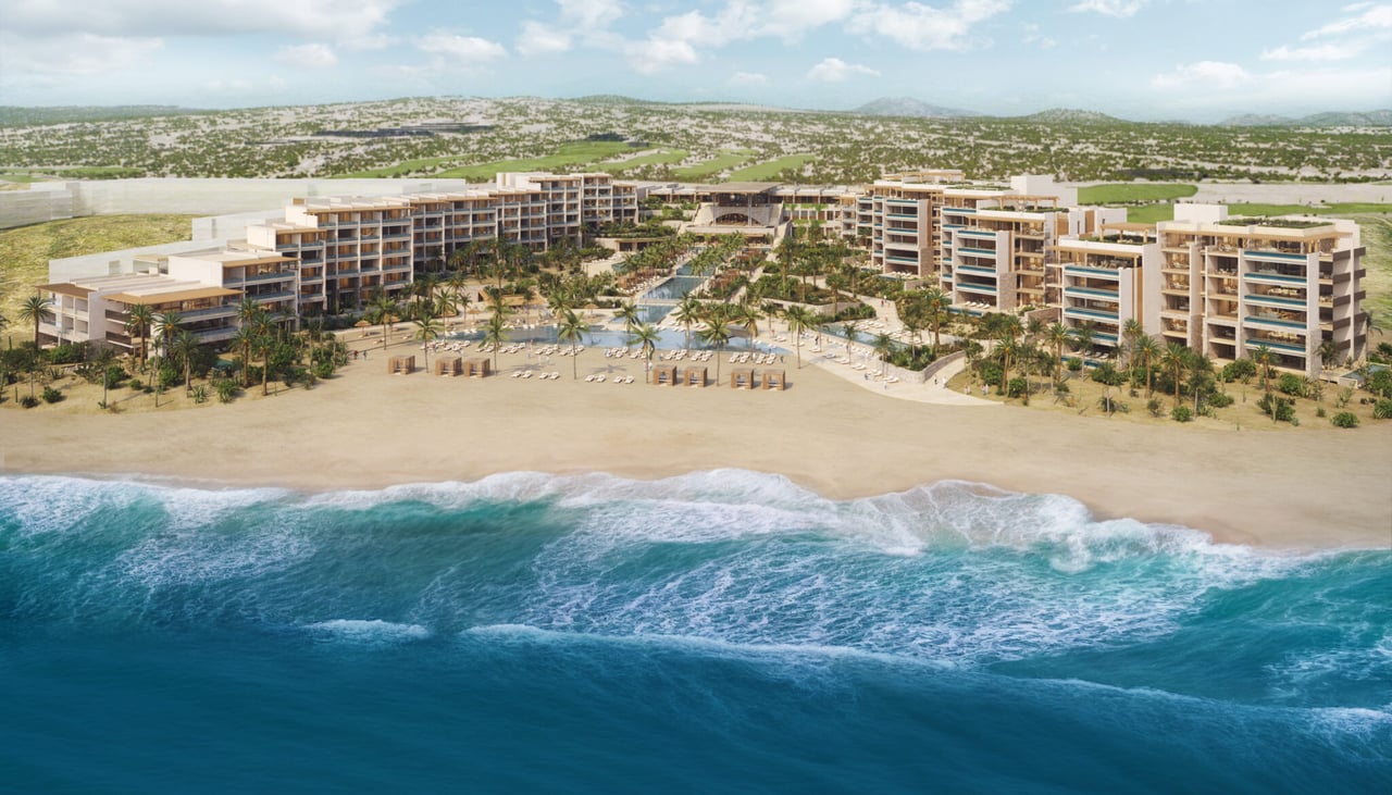 Beachfront resort residences with landscaped pools, a sandy shore, and turquoise ocean.