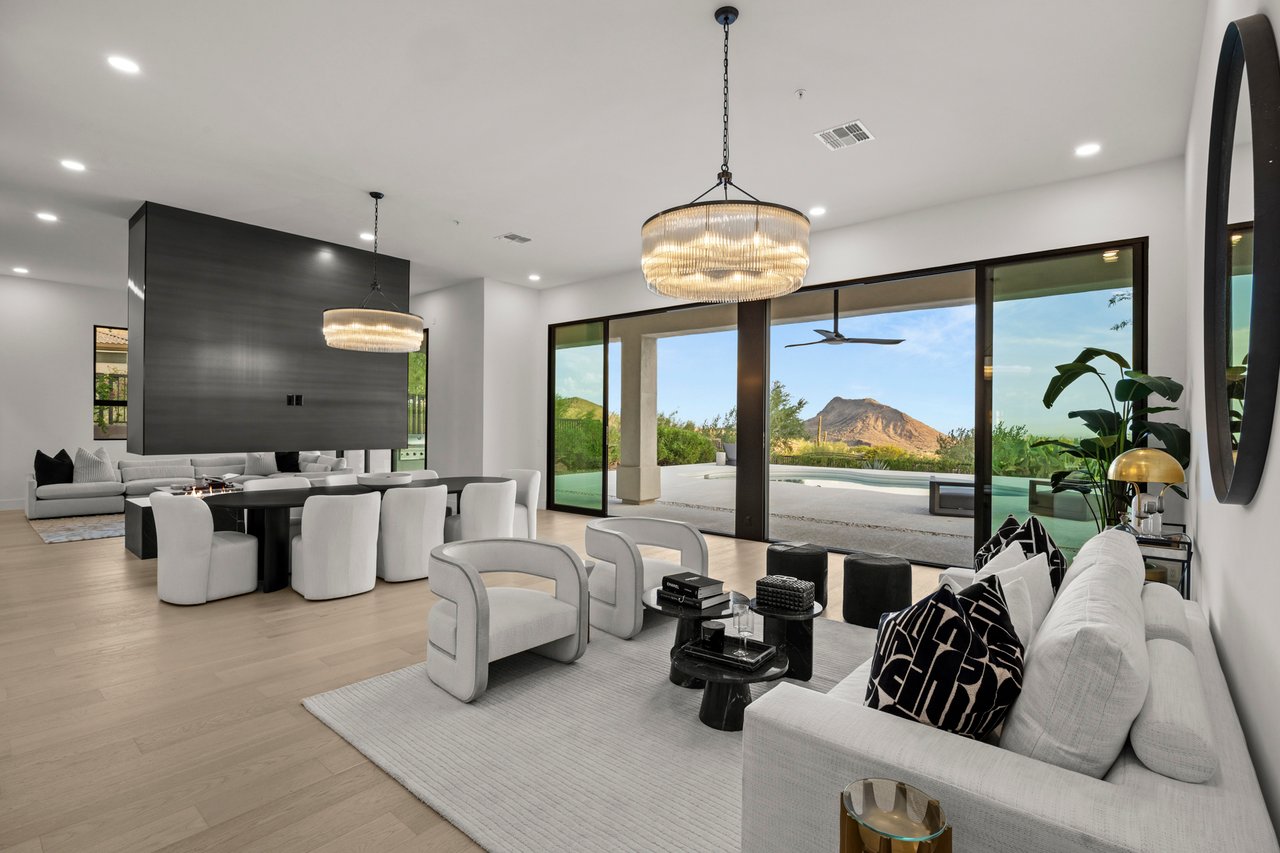 Furnished open-plan living and dining room with glass doors, a pool, and mountain views.