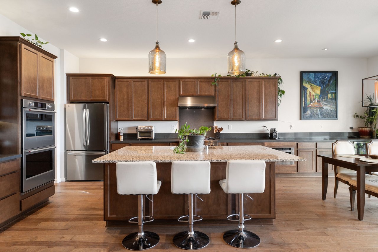Modern kitchen in South Reno Caramella Ranch home with large island, bar seating, pendant lighting, and stainless steel appliances