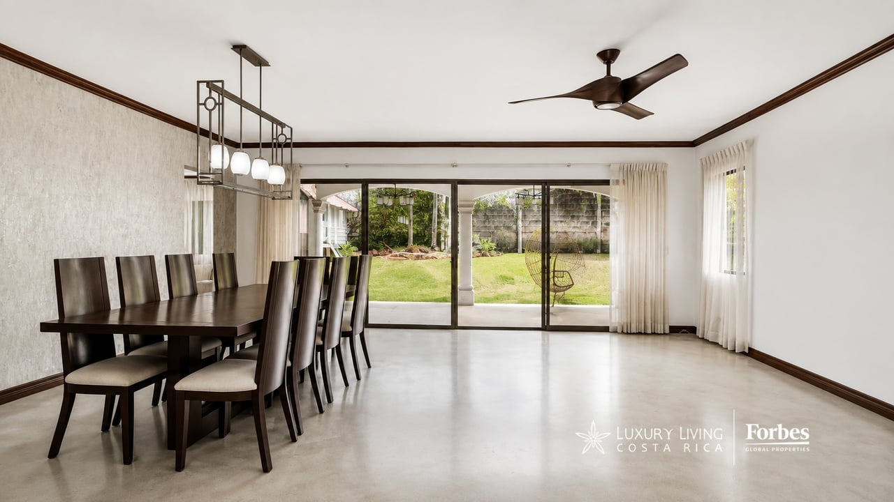 Dining room with a dark wood table, opening through sliding doors to a garden.