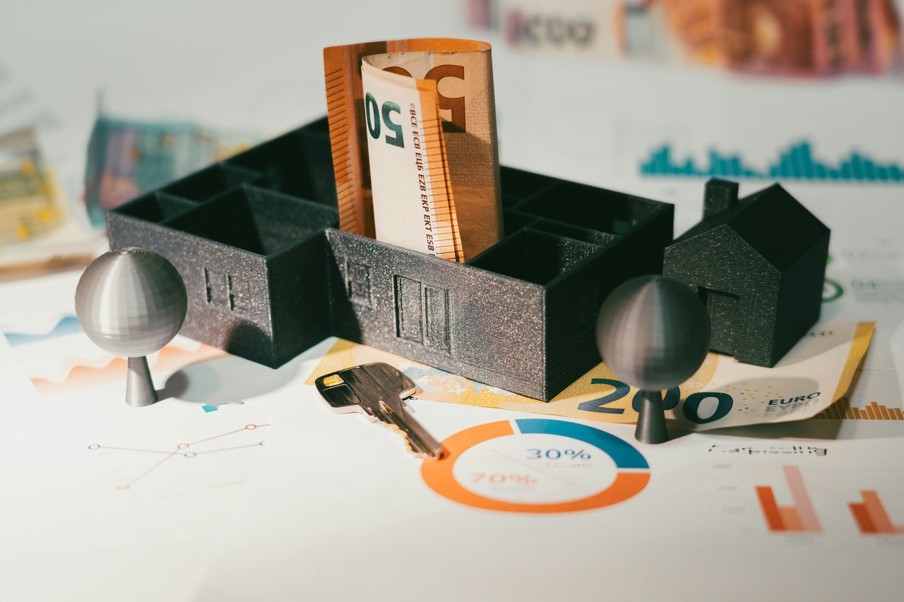 House model on euro banknotes and financial charts, with a key and €50 note.