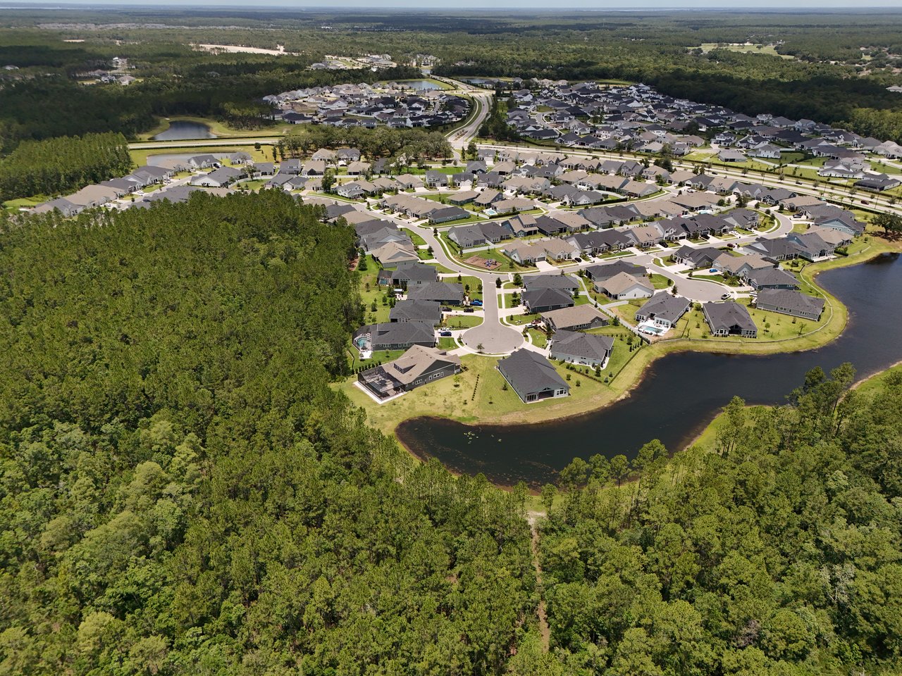 Oak Grove neighborhood of detached homes beside a pond and wooded land.