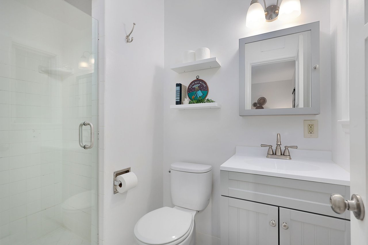 Clean and modern bathroom with glass-enclosed shower, white vanity, and floating shelves