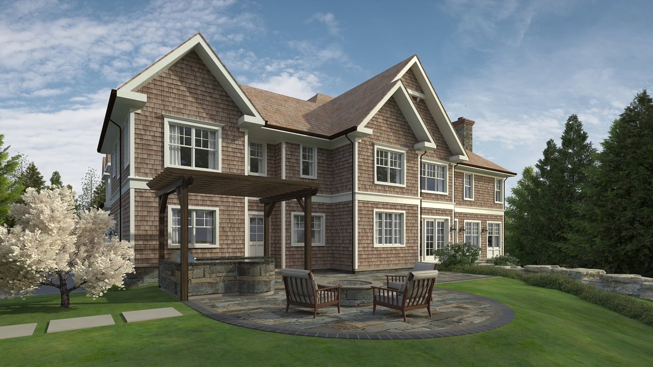 Shingle-style home with a stone patio, outdoor chairs, and a flowering tree in the yard.