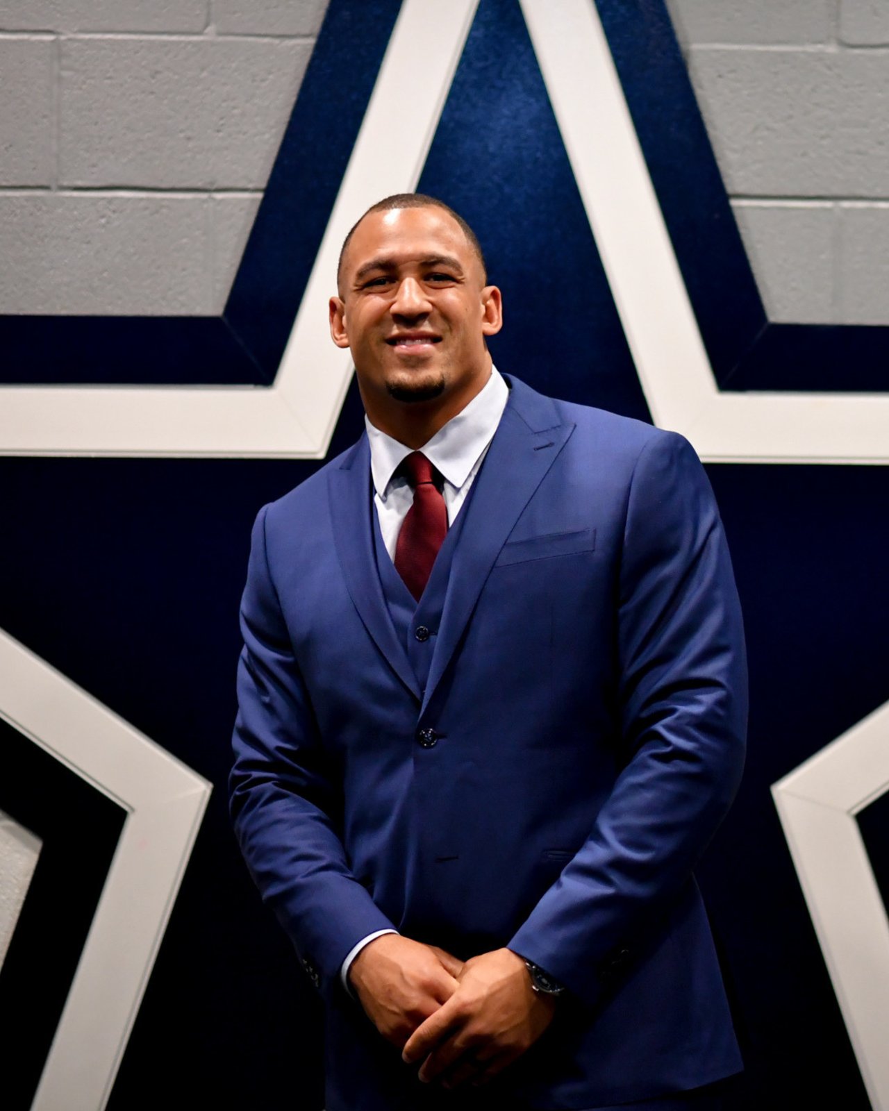 Tyrone Crawford in a blue suit and red tie before a large star emblem.
