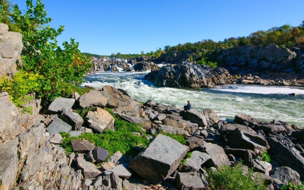 Rocky river rapids at Great Falls, with a lone visitor among the boulders.
