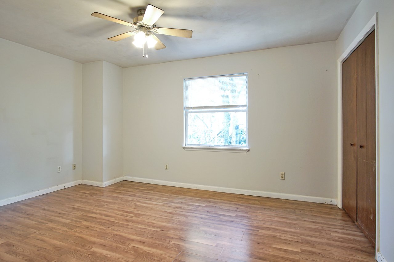 An empty room featuring hardwood floors and a ceiling fan, creating a spacious and airy atmosphere.